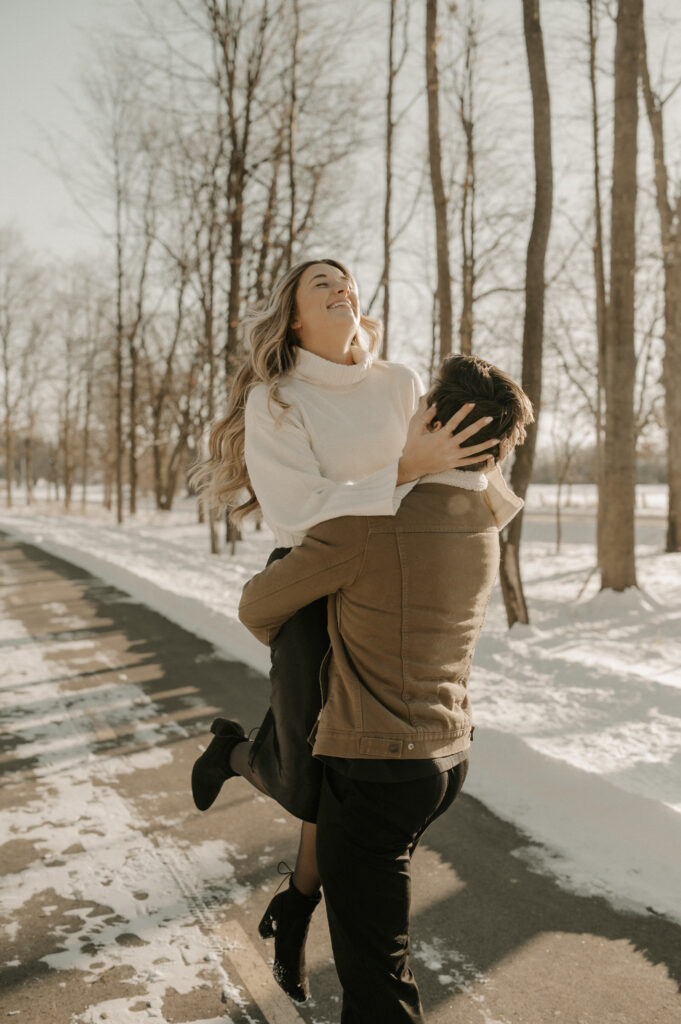 photo of couple laughing together as the man picks up the woman and spins her around getting her to laugh and show real emotion in the photo